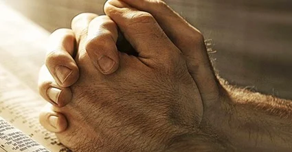 Manos en oración sobre una Biblia abierta